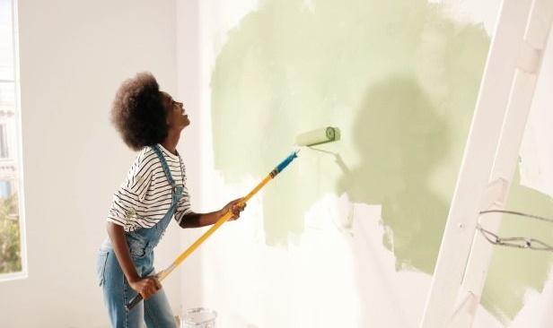 jeune femme en train de peindre un mur avec le prêt personnel travaux GMF